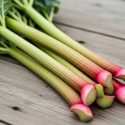Fresh 'Champagne' Rhubarb stalks with vibrant pink and green hues, arranged on a rustic wooden surface, showcasing their natural texture and color.