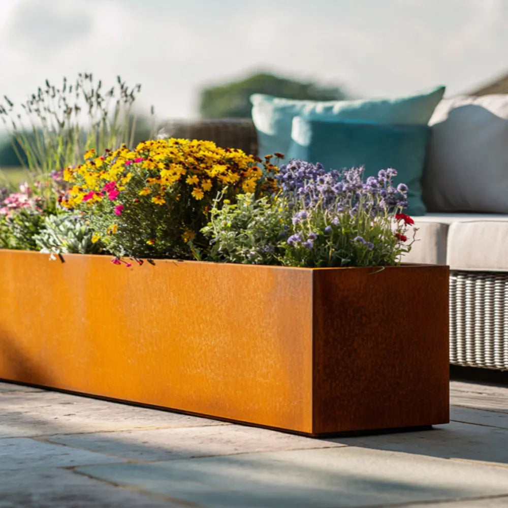 Extra large Corten metal planter with flowers on a patio
