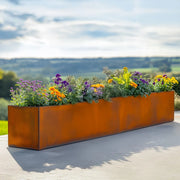 Extra large Corten steel planter with flowers against a scenic background
