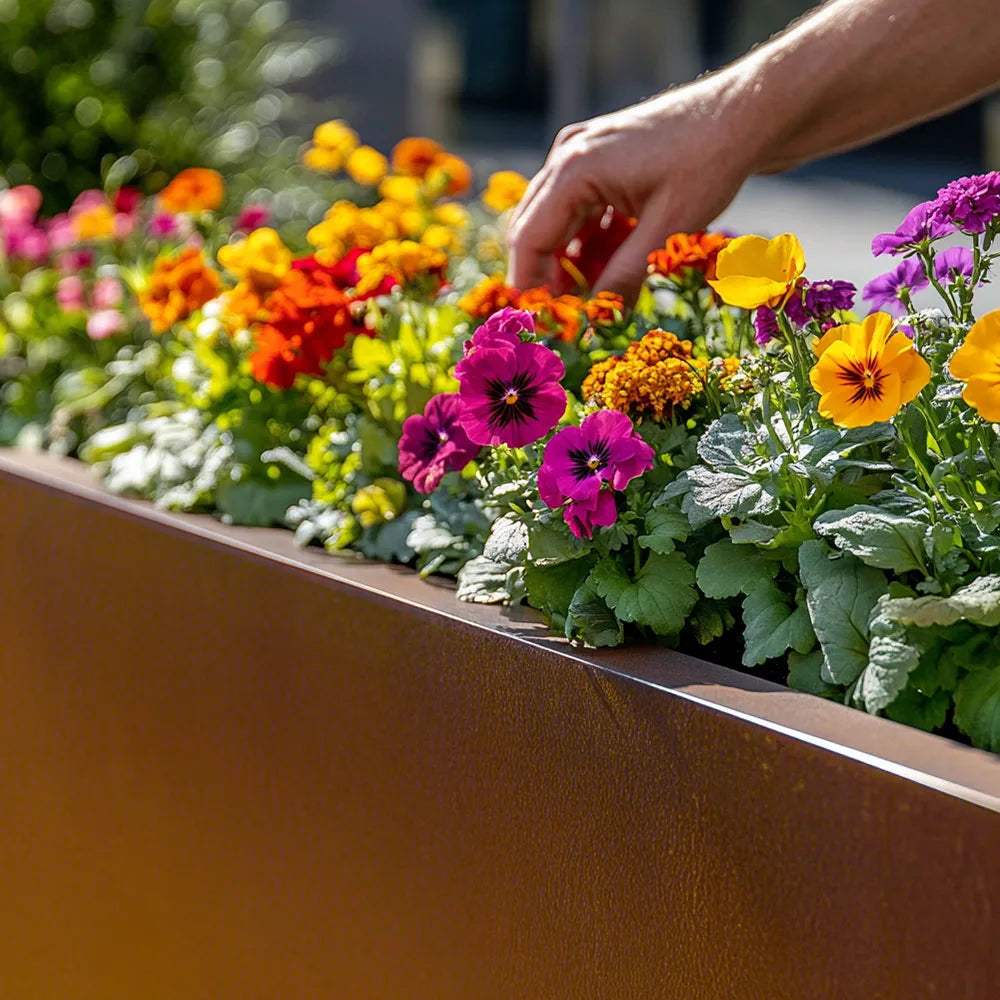 Person arranging colorful flowers in a metal planter