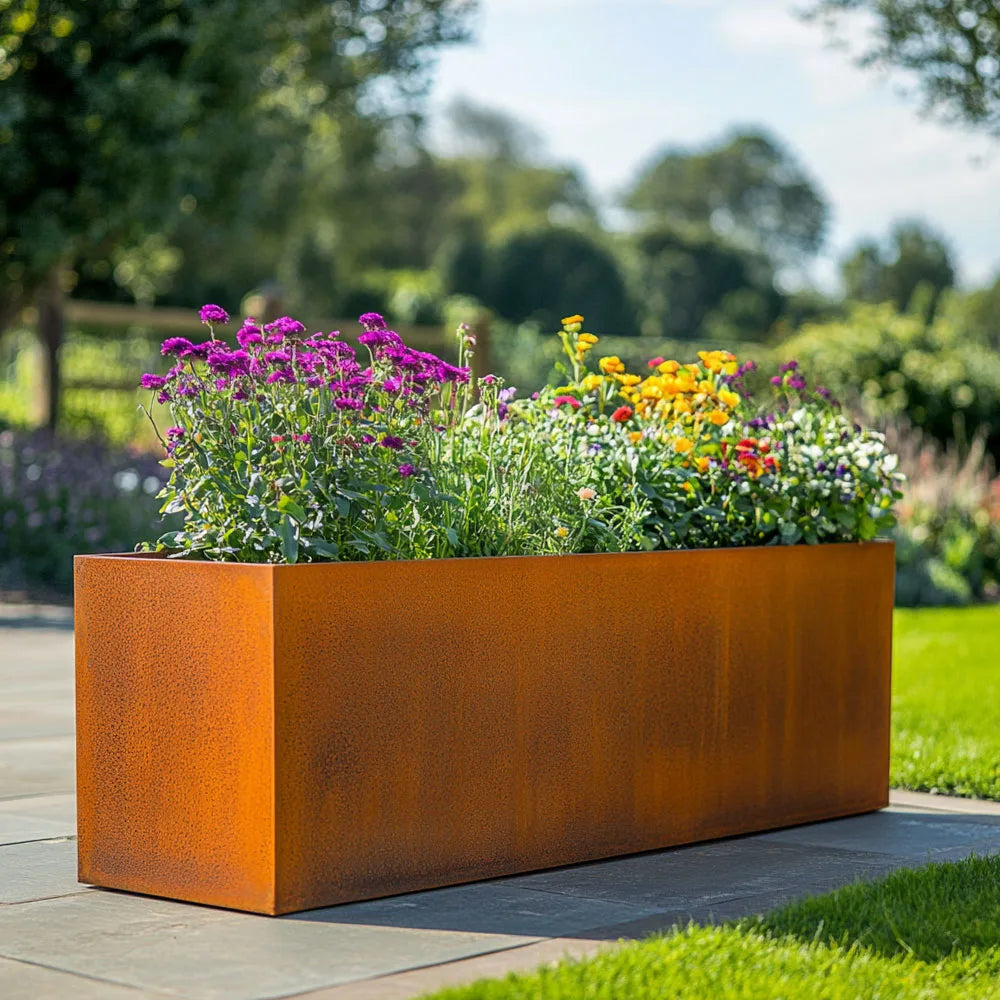 Corten steel trough planter with flowers in a garden setting