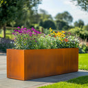 Corten steel trough planter with flowers in a garden setting