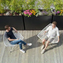 Two men sitting on a wooden deck with a divider planters in the background