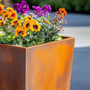 Corten rusted metal planter with colourful flowers outdoors