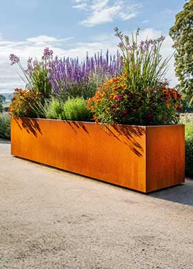 Corten steel planter with flowers against a blue sky