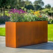 Corten steel rectangular planter with flowers in a garden setting