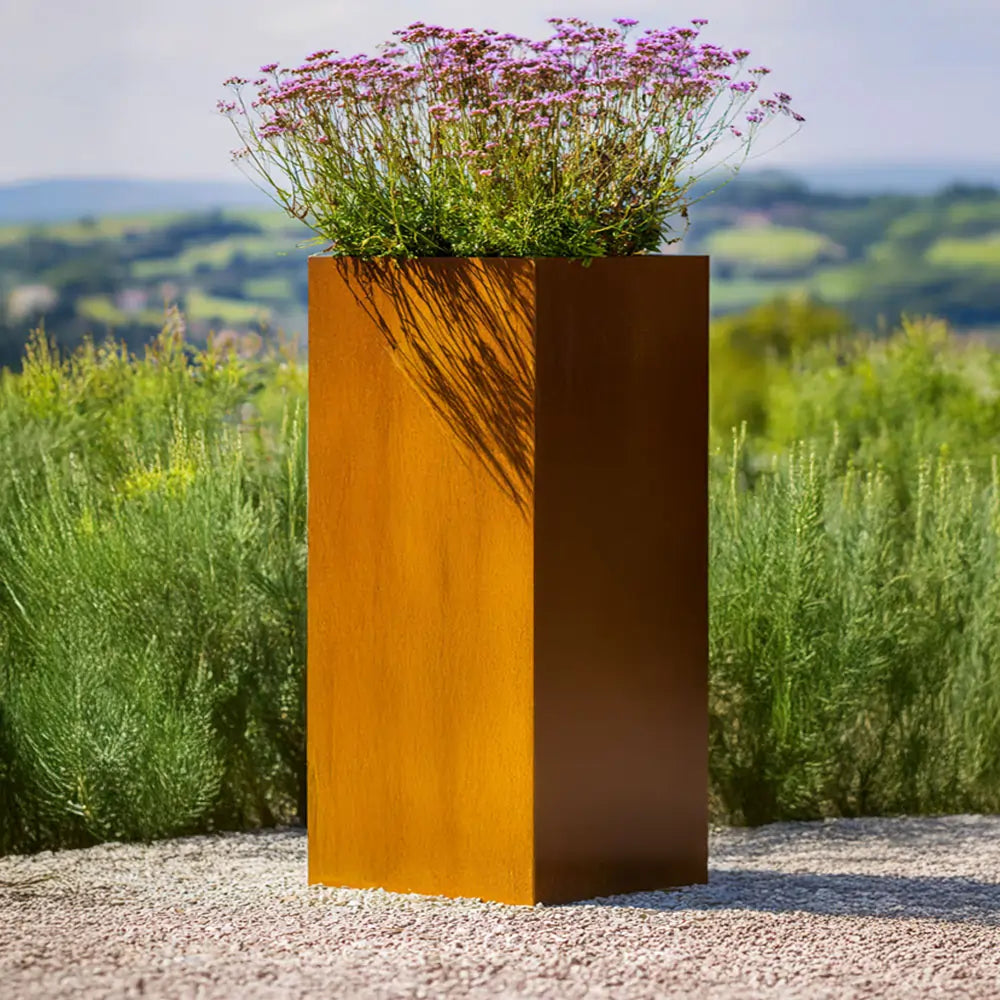 Tall corten steel planter with flowers against a scenic background