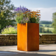 Corten steel planter with flowers in a garden setting