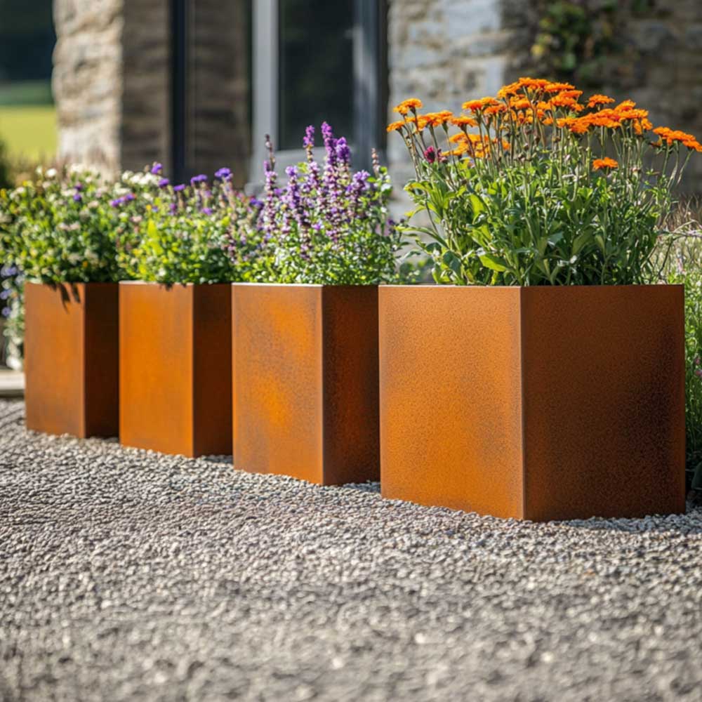 Row of rust-colored metal planters with flowers in a garden setting