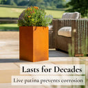 Rust-colored planter with flowers on a patio with outdoor furniture.