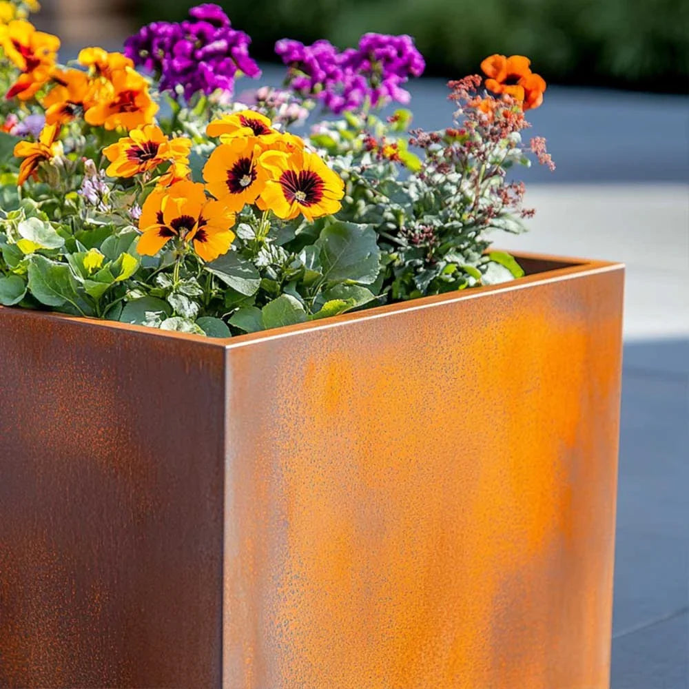 Corten metal planter with colourful flowers on a blurred background