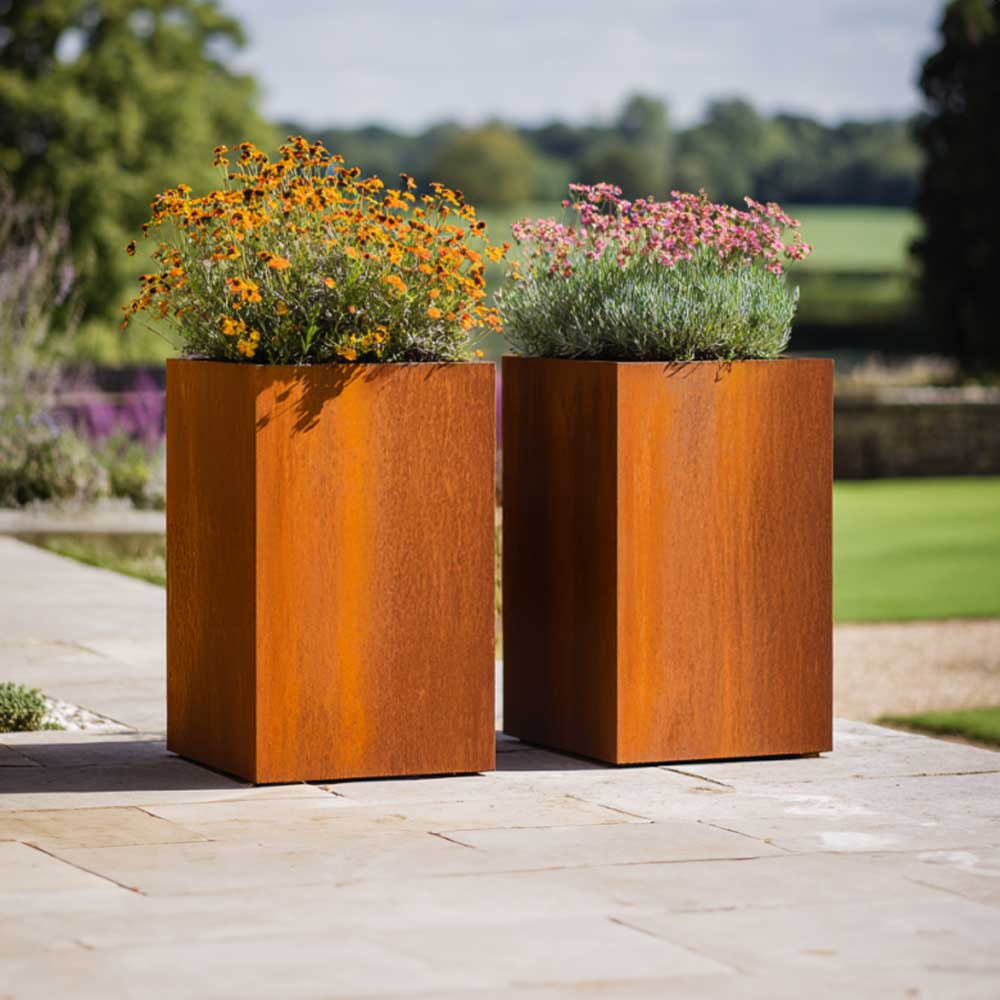 Two rust-colored metal planters with flowers on a patio