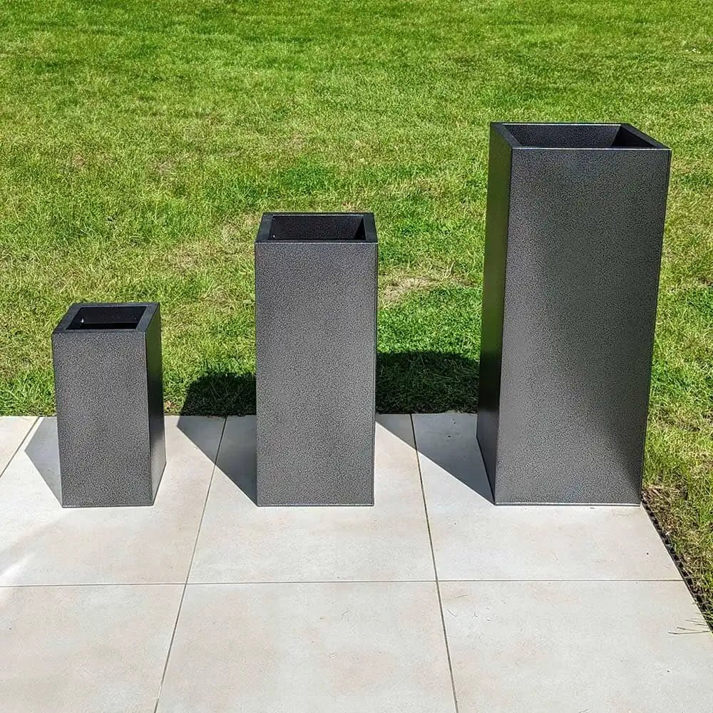 Tall planters standing beside the entrance of a house