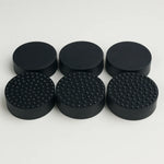 Set of black round rubber feet with textured surface on a white background