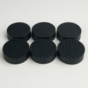 Set of black round rubber feet with textured surface on a white background